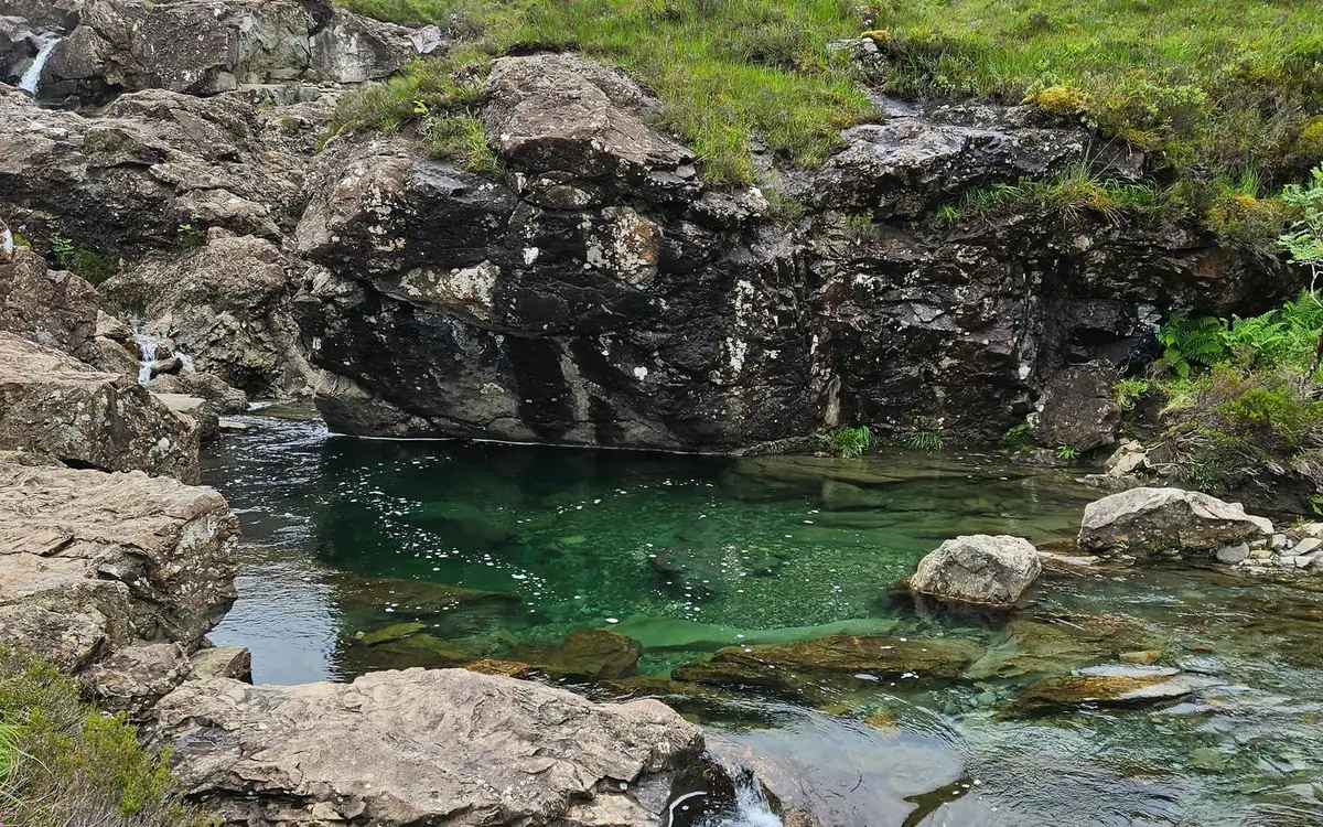 Una pozza verde limpida tra rocce grigie alle Fairy Pools