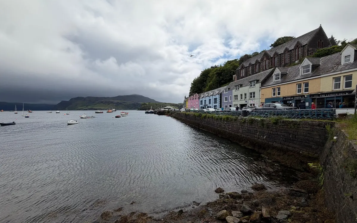 Una fila di case colorate lungo la banchina del porto di Portree, sopra l'acqua calma