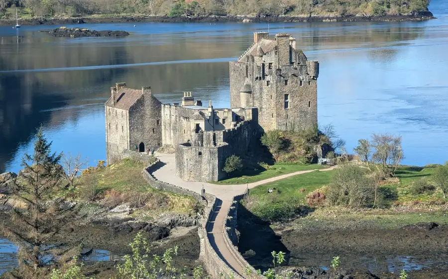 Un castello di pietra sulla sua isola e una passerella, visti dall'alto del loch