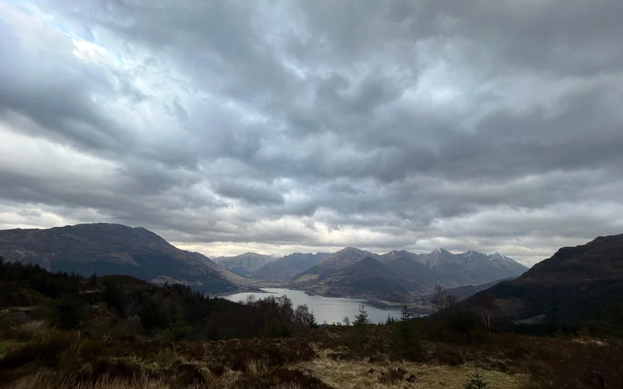 Un lungo loch tra montagne scure sotto pesanti nuvole grigie